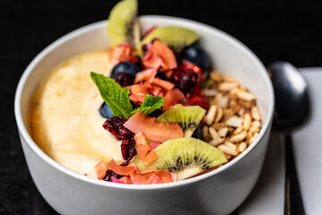 A fresh acai breakfast bowl featuring granola, bananas, strawberries, blueberries and mint