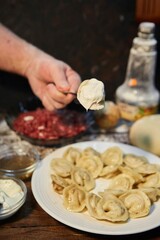 The dish is cooked dumplings. Handmade work. Slavic or Balkan cuisine. Sour cream sauce