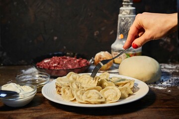 The dish is cooked dumplings. Handmade work. Slavic or Balkan cuisine. Sour cream sauce