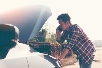 Man opens the hood of the broken down car on the side of the road. Roadside assistance.