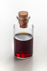 A round glass bottle containing dark amber color essential oil for cosmetics and natural medicine.