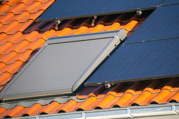 Dachfenster mit Rollladen, daneben Paneele für Solarthermie