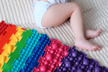 Children's feet on a massage mat. Gymnastics for children, development of motor skills, speech with the help of massage rubber forms of different colors.