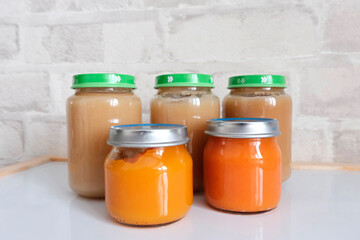 Glass jars for children with mashed potatoes for feeding children up to one year old. Introducing vegetables into a child's diet. Broccoli, carrots, cauliflower. Light background.