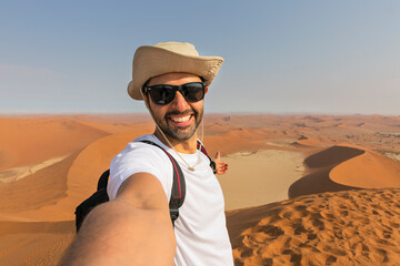 Happy tourist taking selfie on sand dunes in the Namib desert - Namibia