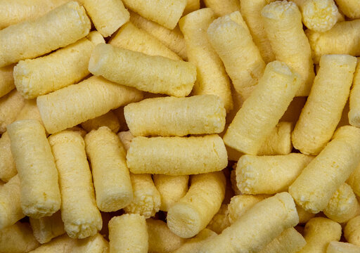 A close-up with many corn puffs. Crunchy corn sticks