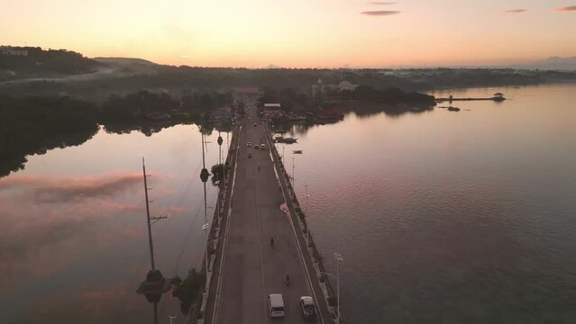 Golden hour aerial view of Dauis bridge traffic and sky reflection on water