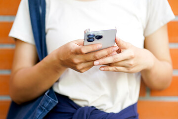 Closeup and crop Asian young female student in casual cloth holding and play smart mobile.