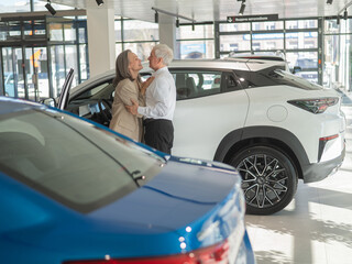 Mature Caucasian couple hugging with happiness while buying a new car. 