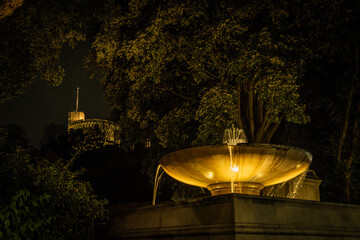 Round Tower of Windsor Castle and decorative water fountains lit at night by lights in the grounds....