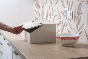 Woman opening wooden bread box on the kitchen counter - obrazy, fototapety, plakaty