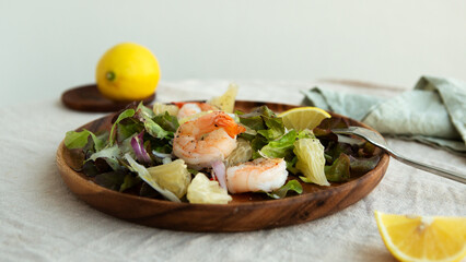 plate with salad with shrimp, pomelo and parmesan on the table