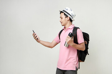 Asian man backpacker hold mobile phone and tumbler bottle. travelling concept. on isolated background