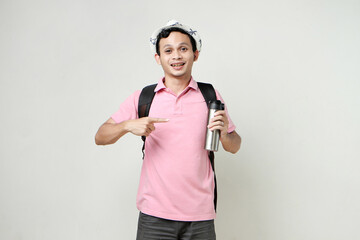 Asian man backpacker hold tumbler bottle and pointing finger gesture. travelling concept. on isolated background