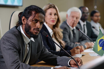Businessman speaking in microphone and talking to journalists during business conference