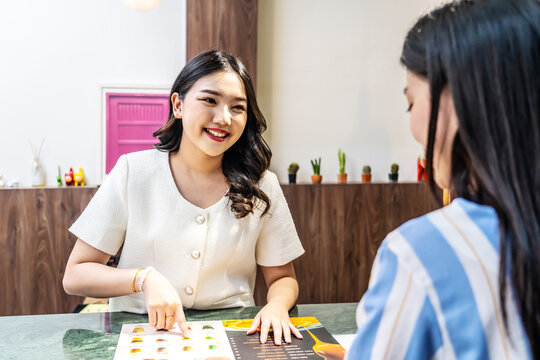 Young asian beautiful female customer select coffee or juice items. with a young woman barista working at the cafe or restaurants counter, entrepreneurial concept Starting a small business, lifestyle - Powered by Adobe