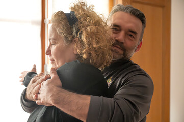 A masseuse performs back stretches on an adult woman in her home.