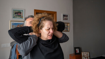 A masseuse performs back stretches on an adult woman in her home.