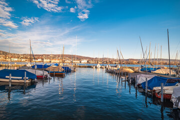 Small sail boats docked on a pier on lake Zurich. Sunny autumn day, no people