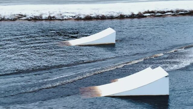 Wakeboarder sliding across the water in snowy conditions.