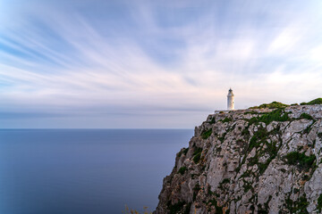 Fototapeta na wymiar Dramatic Long Exposure of Lighthouse Atop Cliff Overlooking Silky Ocean