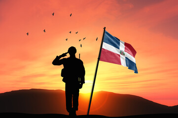 Silhouette of a soldier with the Dominican Republic flag stands against the background of a sunset or sunrise. Concept of national holidays. Commemoration Day.