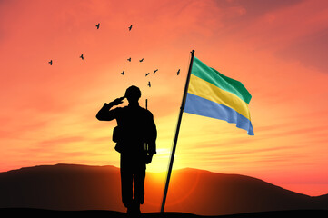 Silhouette of a soldier with the Gabon flag stands against the background of a sunset or sunrise. Concept of national holidays. Commemoration Day.