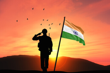 Silhouette of a soldier with the India flag stands against the background of a sunset or sunrise....