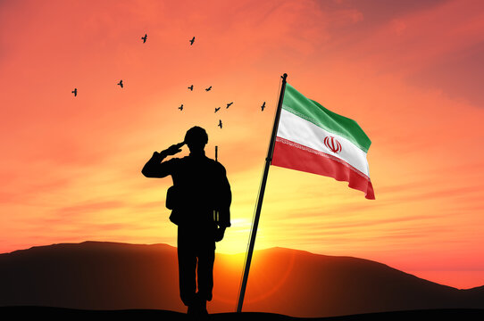 Silhouette of a soldier with the Iran flag stands against the background of a sunset or sunrise. Concept of national holidays. Commemoration Day.
