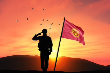 Silhouette of a soldier with the Kyrgyzstan flag stands against the background of a sunset or...