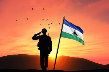 Silhouette of a soldier with the Lesotho flag stands against the background of a sunset or sunrise. Concept of national holidays. Commemoration Day.