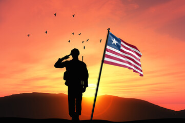 Silhouette of a soldier with the Liberia flag stands against the background of a sunset or sunrise. Concept of national holidays. Commemoration Day.