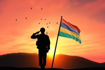 Silhouette of a soldier with the Mauritius flag stands against the background of a sunset or sunrise. Concept of national holidays. Commemoration Day.