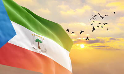 Waving flag of Equatorial Guinea against the background of a sunset or sunrise. Equatorial Guinea...