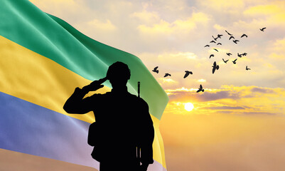 Silhouette of a soldier with the Gabon flag stands against the background of a sunset or sunrise. Concept of national holidays. Commemoration Day.