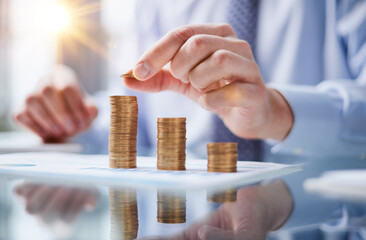 Businessman stacking coins on table, business growth concept. Hand puts coin to stack.