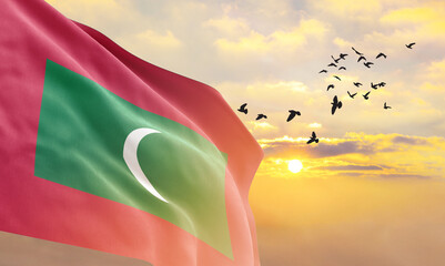 Waving flag of Maldives against the background of a sunset or sunrise. Maldives flag for...