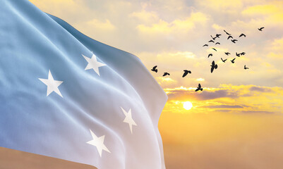 Waving flag of Micronesia against the background of a sunset or sunrise. Micronesia flag for...