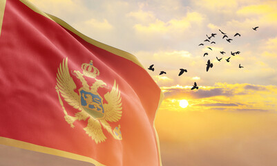 Waving flag of Montenegro against the background of a sunset or sunrise. Montenegro flag for Independence Day. The symbol of the state on wavy fabric. - obrazy, fototapety, plakaty