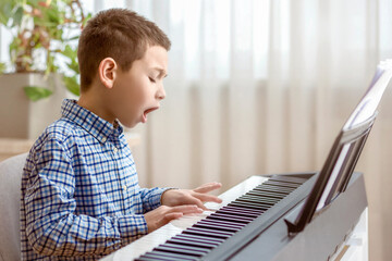 Playing the Piano. Happy Emotional Little Boy Child Pianist Leaning to Play the Piano and Singing...