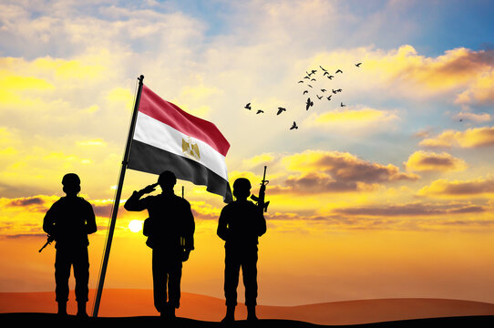 Silhouettes of soldiers with the Egypt flag stand against the background of a sunset or sunrise. Concept of national holidays. Commemoration Day.