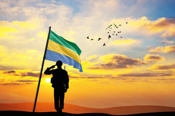 Silhouette of a soldier with the Gabon flag stands against the background of a sunset or sunrise. Concept of national holidays. Commemoration Day.