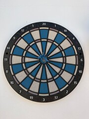 Dartboard with blue and black arrows on a white wall.