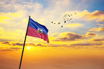 Waving flag of Haiti against the background of a sunset or sunrise. Haiti flag for Independence Day. The symbol of the state on wavy fabric.