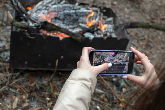 Woman taking picture of a fire in grill on a smartphone	