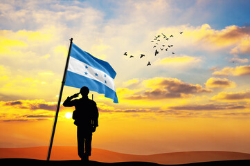 Silhouette of a soldier with the Honduras flag stands against the background of a sunset or sunrise. Concept of national holidays. Commemoration Day.
