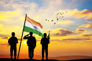 Silhouettes of soldiers with the India flag stand against the background of a sunset or sunrise....