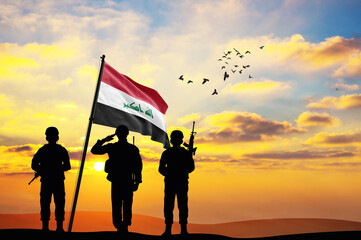 Silhouettes of soldiers with the Iraq flag stand against the background of a sunset or sunrise. Concept of national holidays. Commemoration Day.