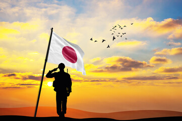 Silhouette of a soldier with the Japan flag stands against the background of a sunset or sunrise....