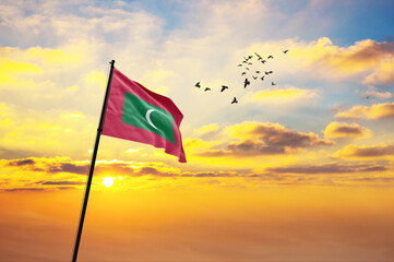 Waving flag of Maldives against the background of a sunset or sunrise. Maldives flag for Independence Day. The symbol of the state on wavy fabric. - obrazy, fototapety, plakaty